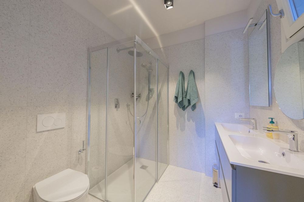 Duschbad mit Terrazzo-Fliesen und Doppelwaschtisch