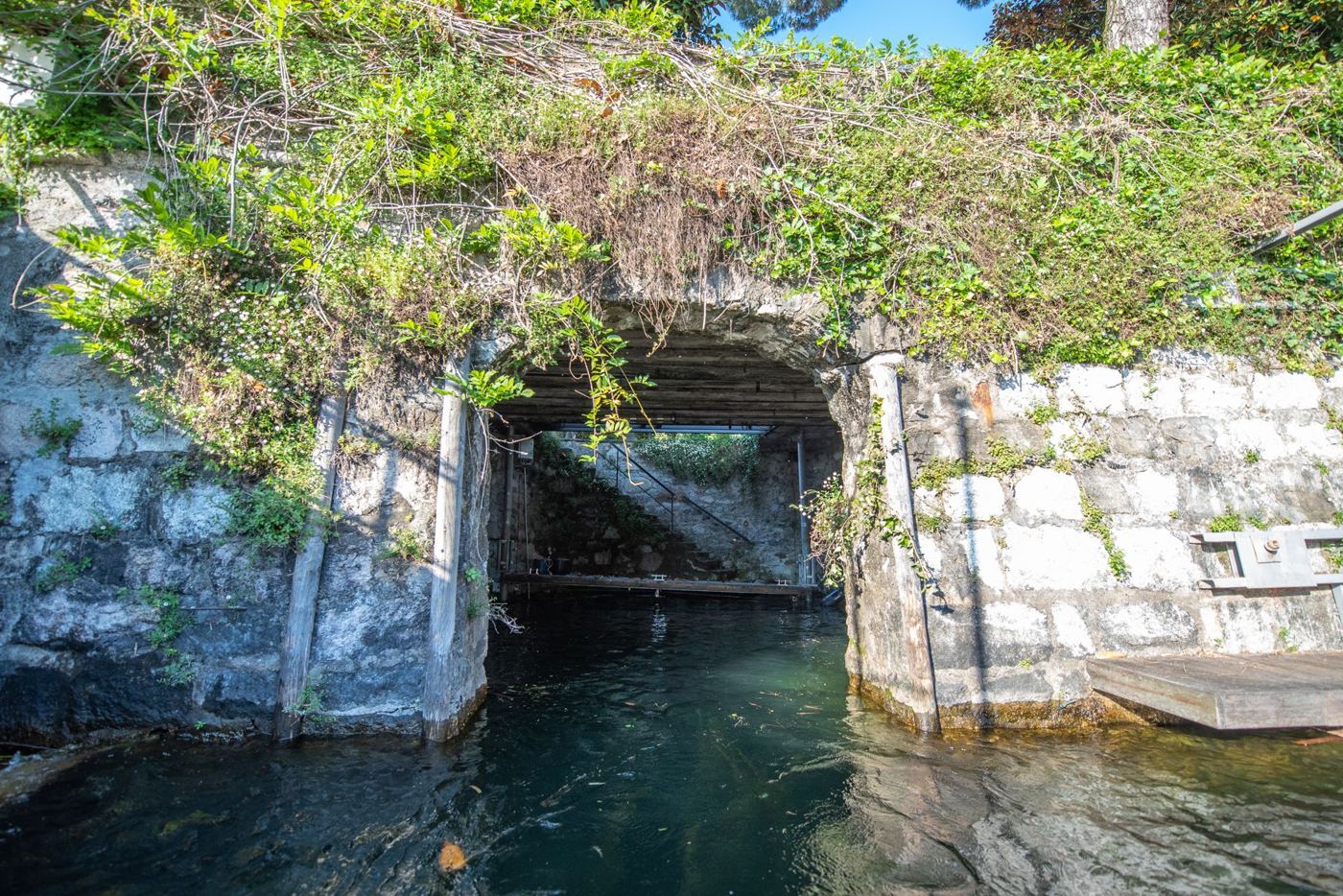 Das alte Bootshaus des Hafens mit Steinbogen, direkt am See