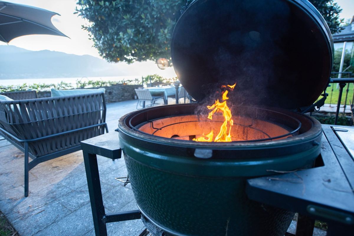 Big Green Egg Grill mit Feuer auf der Terrasse am See