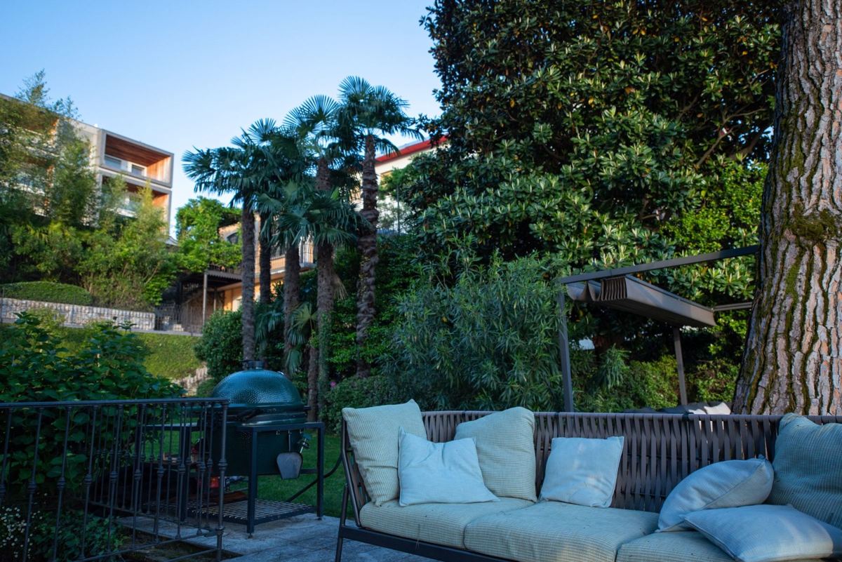 Lounge-Sofa mit Kissen im Garten unter Palmen