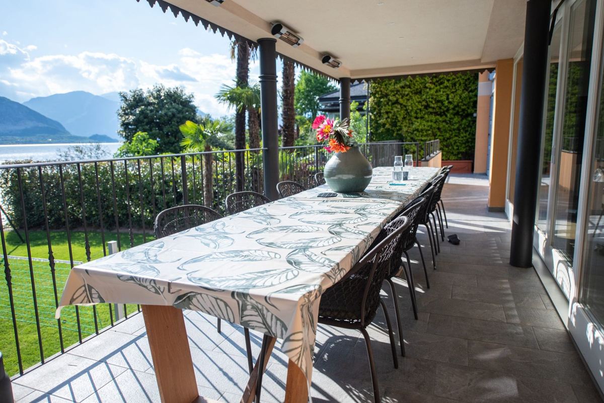Langer gedeckter Tisch auf der überdachten Terrasse mit Seeblick