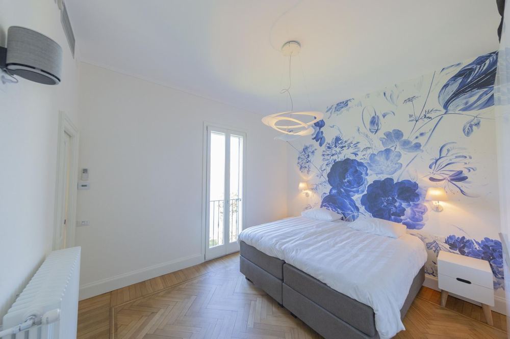Schlafzimmer mit blauer Blumentapete und Balkontür