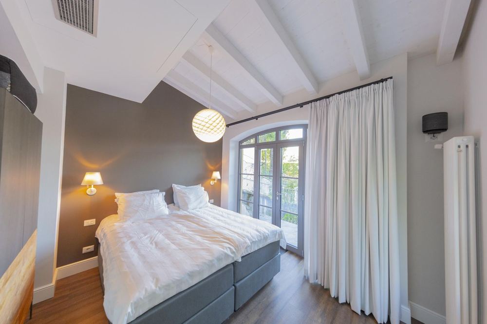 Schlafzimmer mit weißen Holzbalken und Balkontür